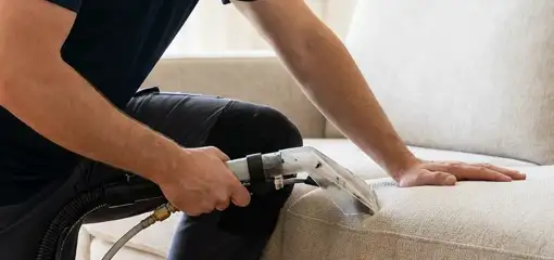 Professional upholstery cleaner deep-cleaning a fabric sofa with a handheld extraction tool, Hialeah, FL.